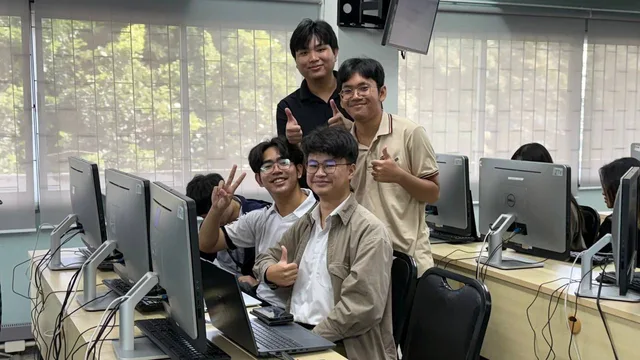 Four workshop participants posing together beside their laptops and lab computers