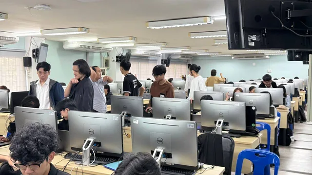 Students working and talking together among the computers in the CMU workshop room